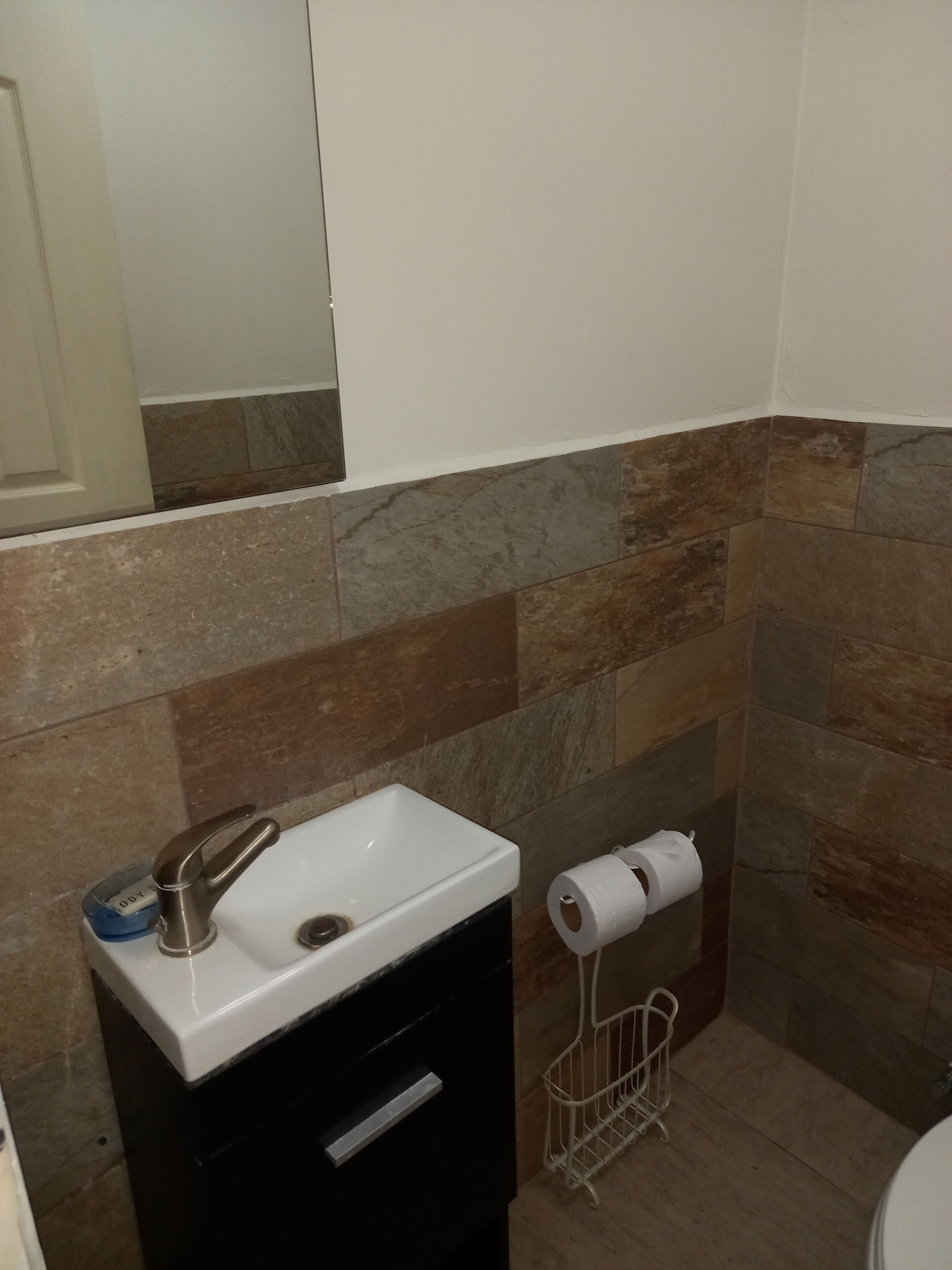 A bathroom with a white sink, a mirror, and a toilet.