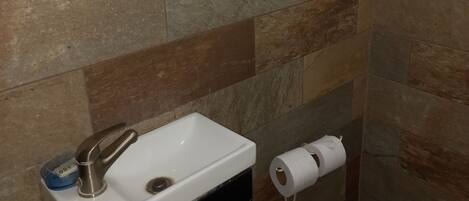 A bathroom with a white sink, a mirror, and a toilet.