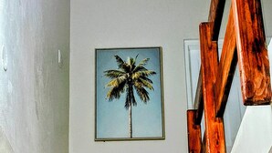 A staircase with a wooden handrail and a framed picture of a palm tree on the wall. - Ella's Park View Townhouse Crown Point (Crown Point)