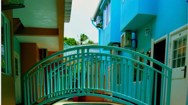 A swimming pool with a curved bridge, surrounded by a tiled deck and a building with a blue exterior. - Ella's Park View Townhouse Crown Point (Crown Point)