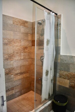 A shower with a glass door, a pineapple-themed shower curtain, and a tiled wall. - Ella's Park View Townhouse Crown Point (Crown Point)