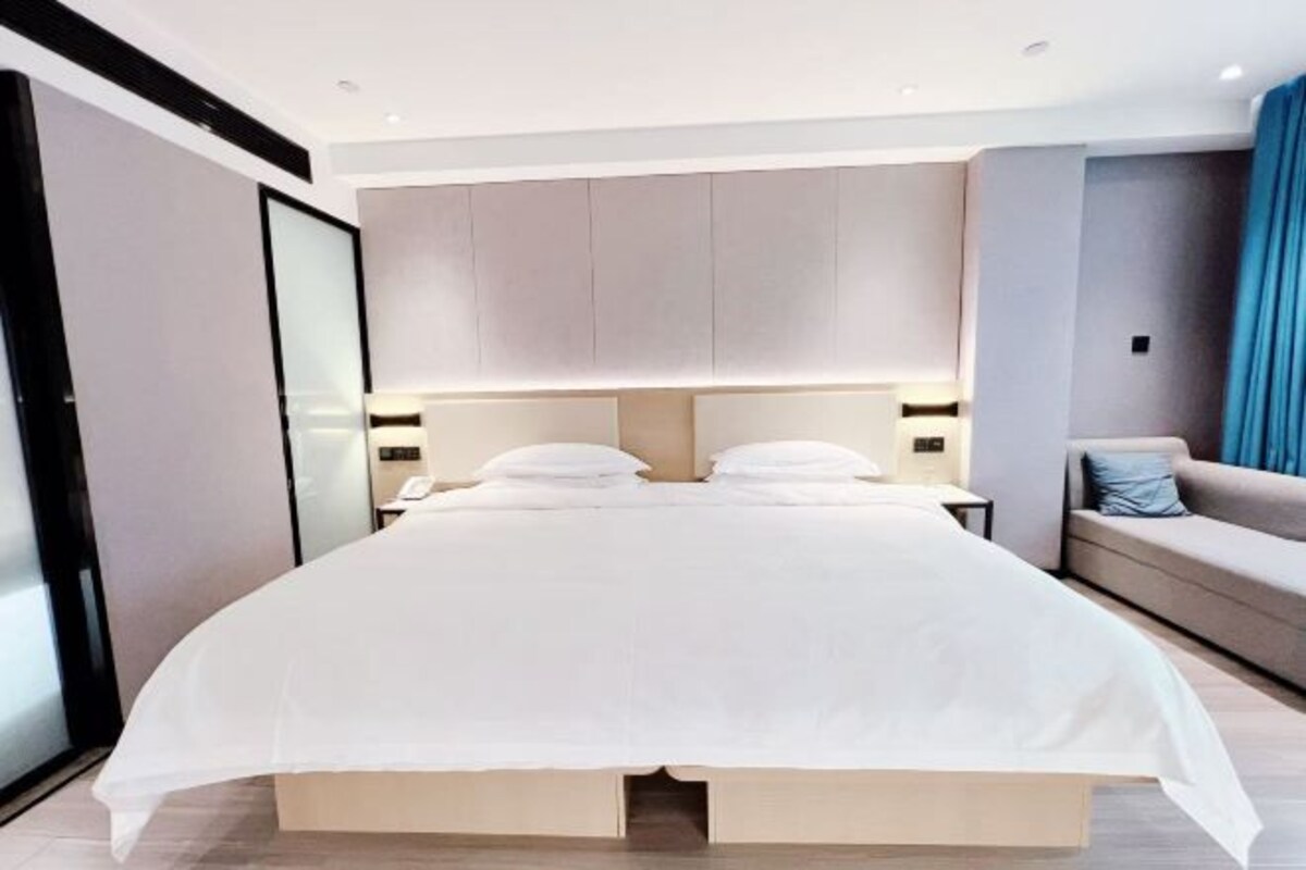 A modern bedroom with a large bed, a sofa, and a nightstand.