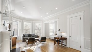 Amplia sala de estar con una mesa de comedor preparada para cuatro personas, un sofá y una mesa de centro.