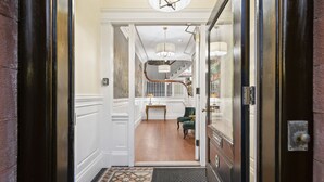 Una entrada imponente con una puerta de madera, una escalera que conduce a un balcón y un sillón verde en el vestíbulo.