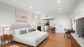 A modern bedroom with a large bed, bedside tables, a desk, and a television.