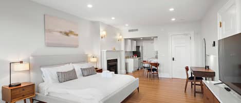 A modern bedroom with a large bed, bedside tables, a desk, and a television.