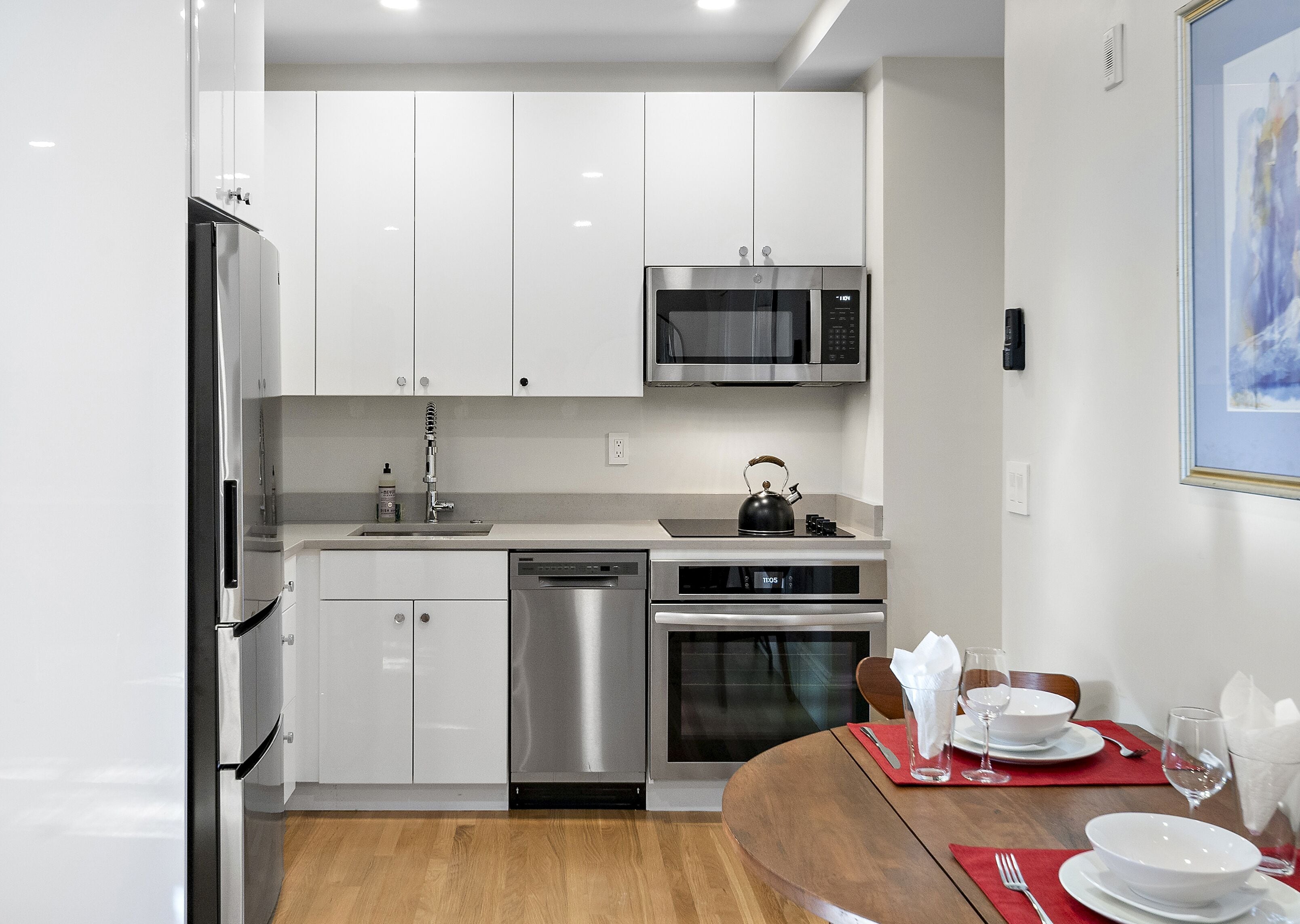 A modern kitchen with stainless steel appliances, a microwave, and a kettle on the countertop.