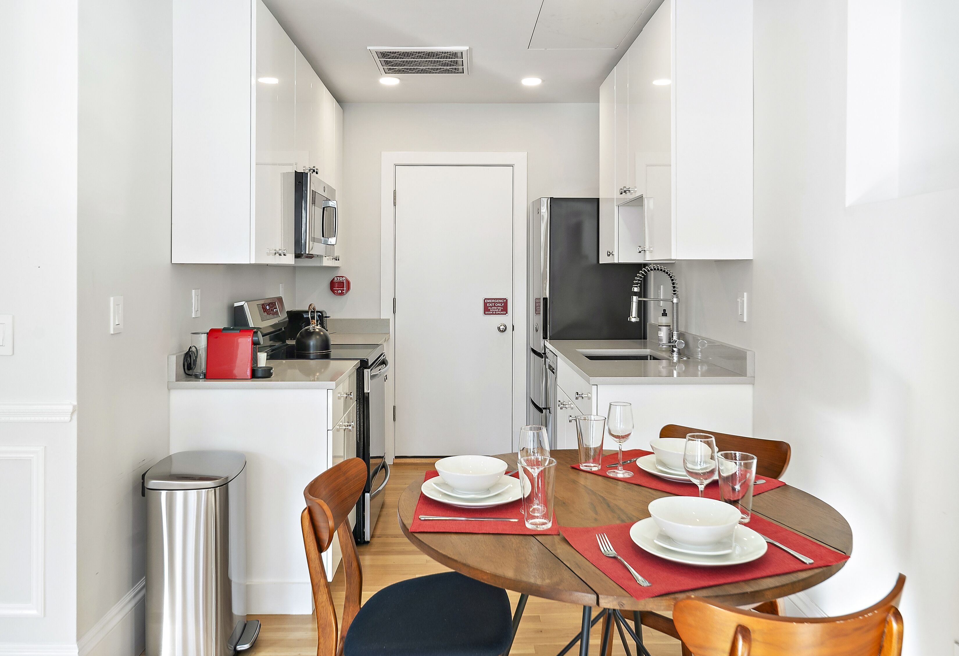 A compact kitchen with white cabinets, a microwave, and a stainless steel sink.