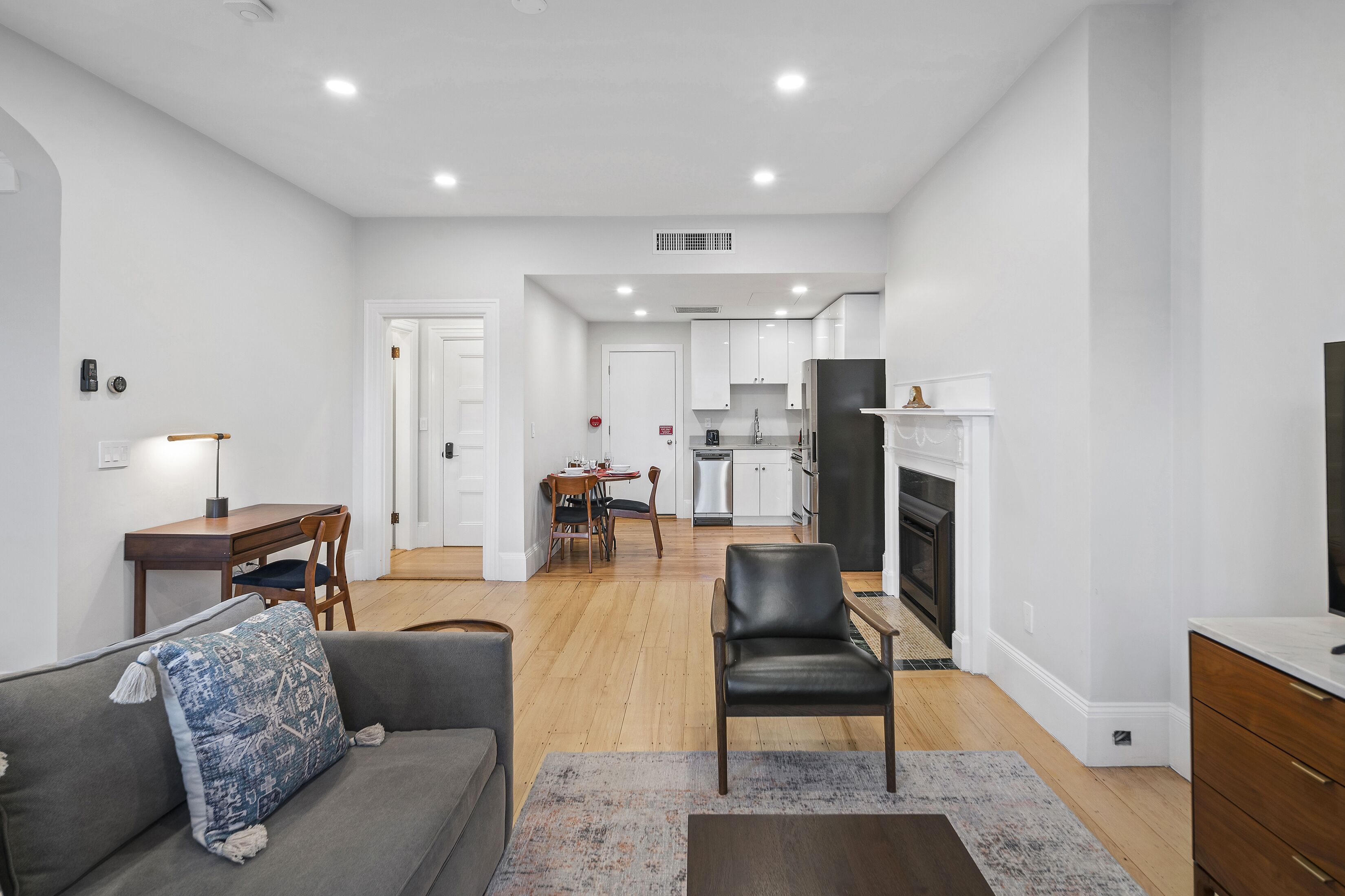 Una sala moderna con un sofá, un sillón y una zona de comedor con mesa y sillas.