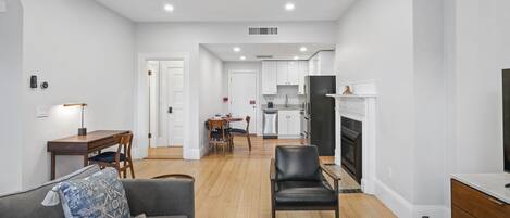 Una sala moderna con un sofá, un sillón y una zona de comedor con mesa y sillas.