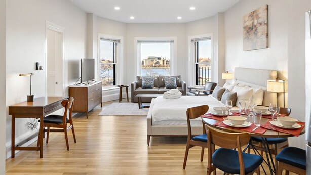 Una habitación de hotel moderna con cama, escritorio, sofá y zona de comedor.