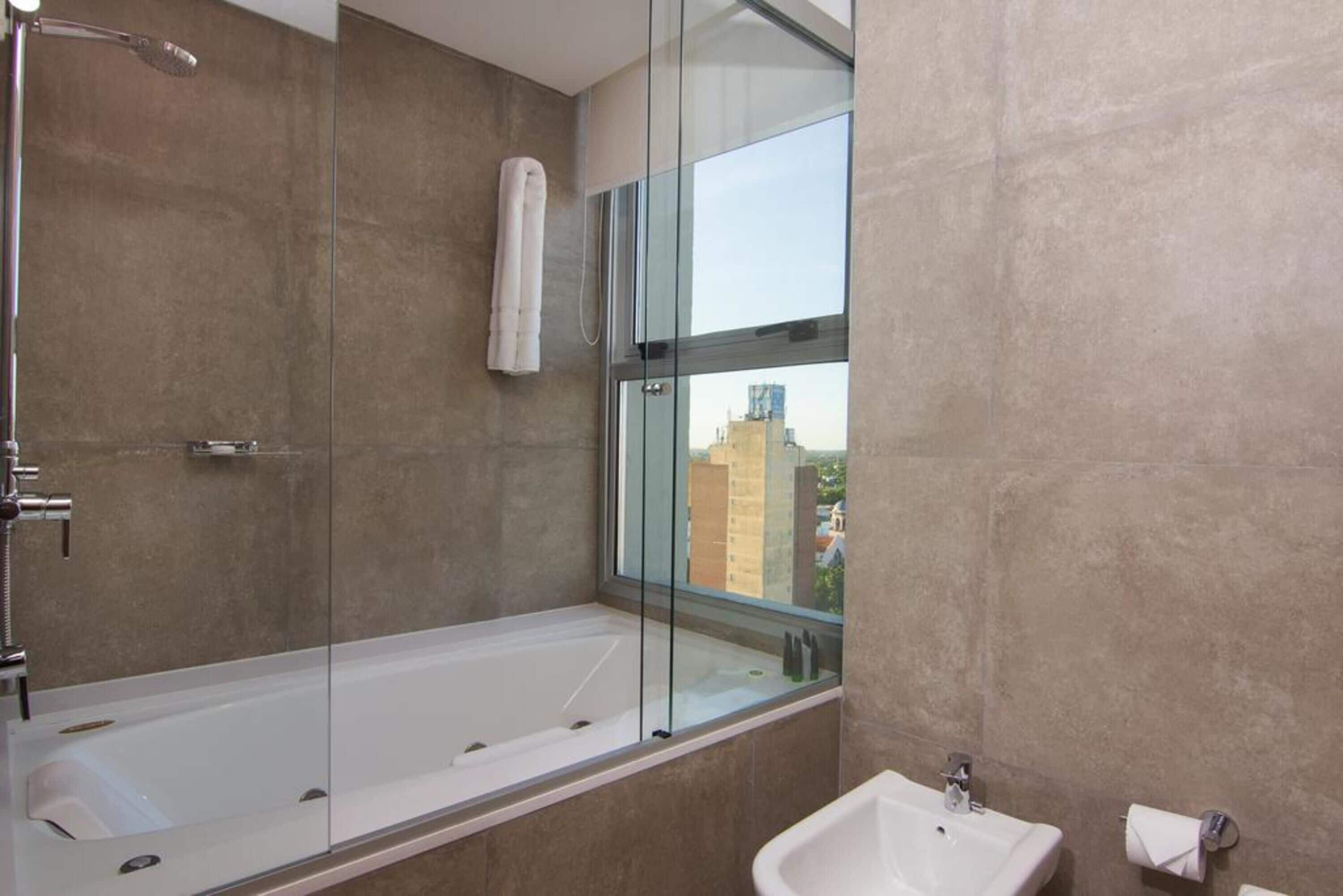 A modern bathroom with a glass-enclosed bathtub, a sink, and a towel rack.