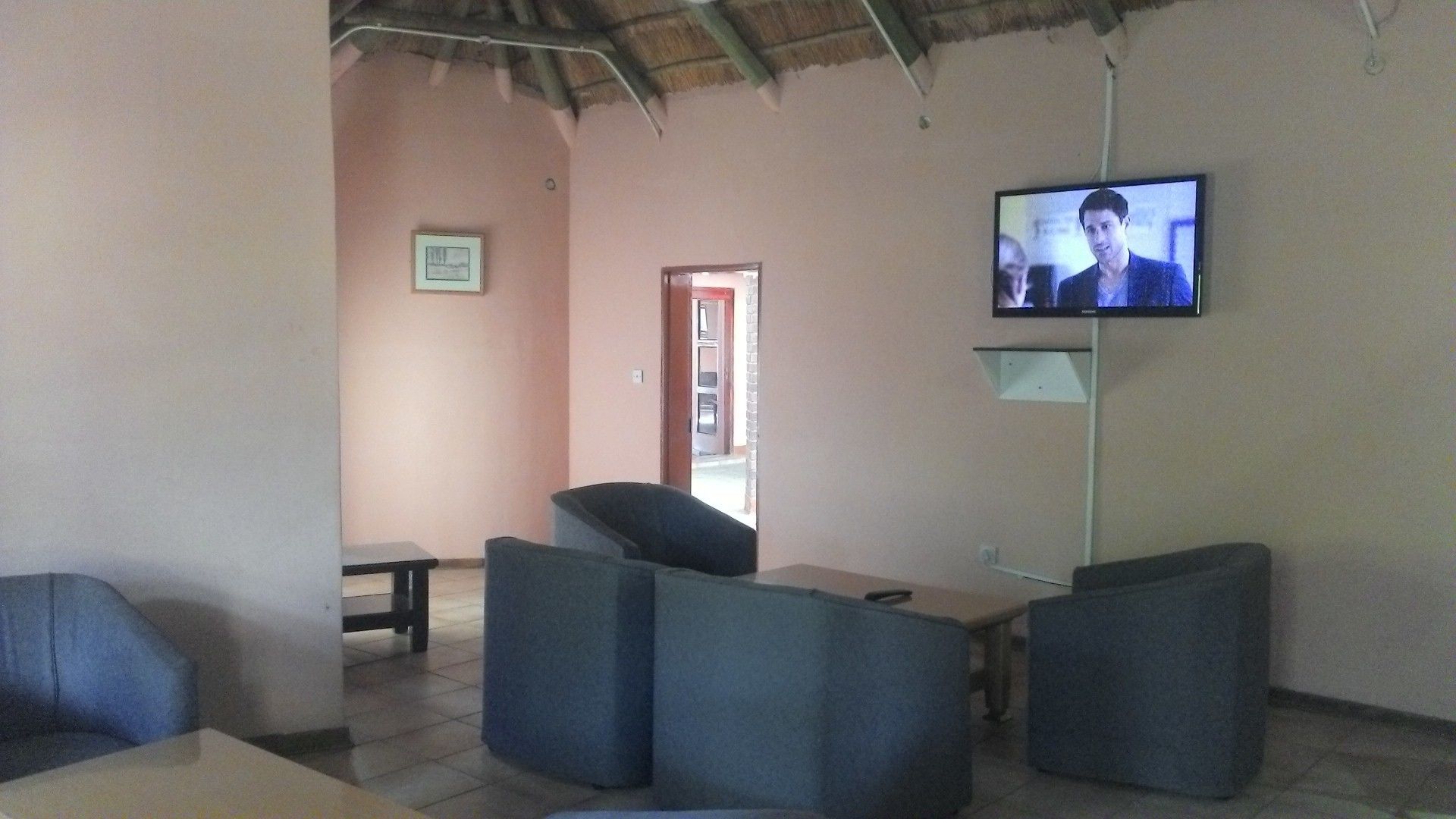A living room with a television mounted on the wall, a small table, and several chairs.