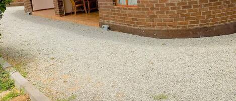 A building with a thatched roof and brick walls, a table and chairs outside, and a gravel ground.
