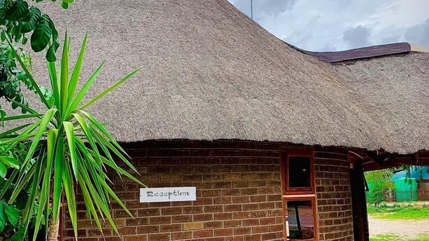 A thatched-roof building with a brick lower section, labeled "Reception." - Echo Lodge (Kang)