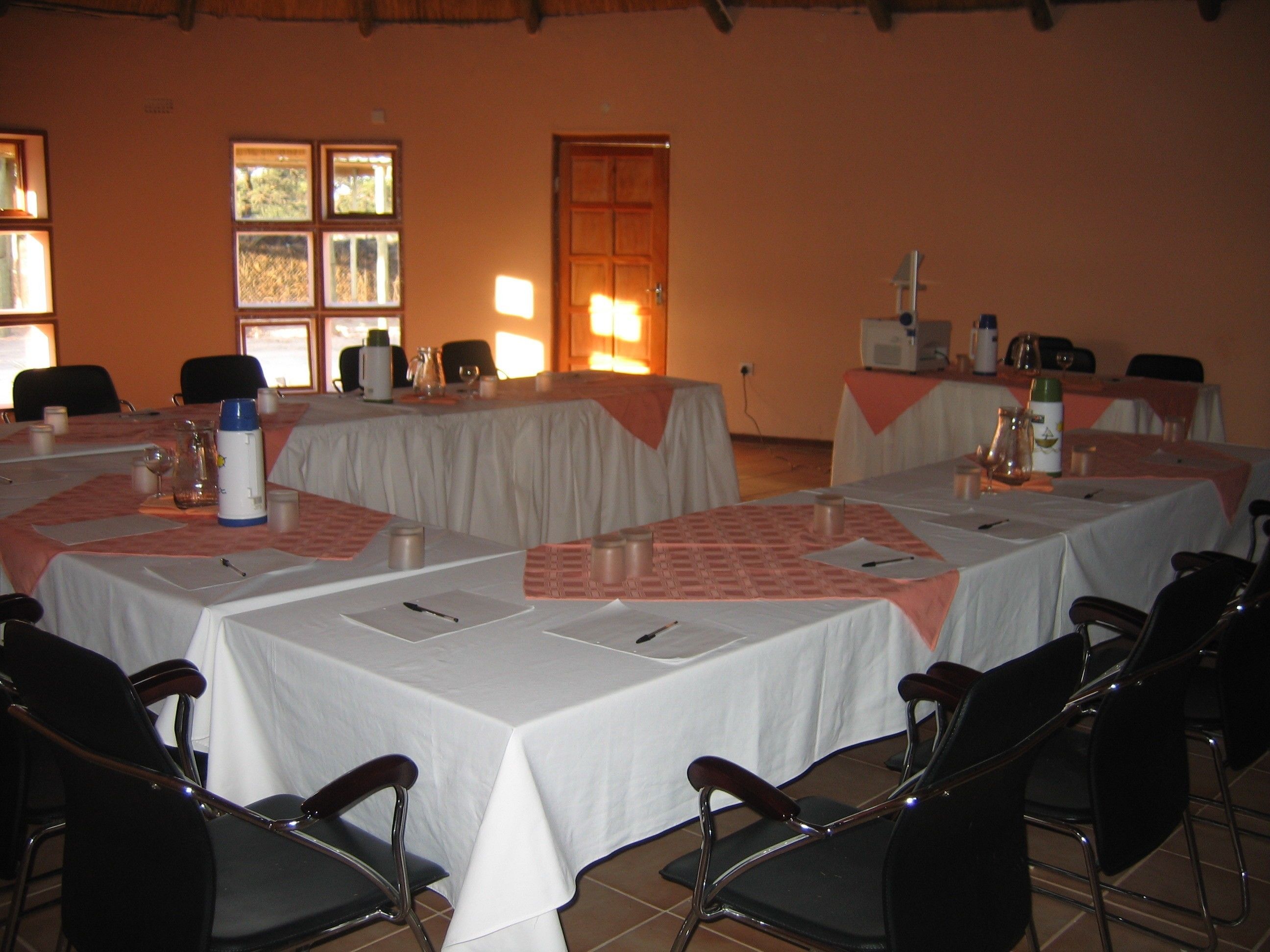 Un salón de conferencias con varias mesas, sillas y una puerta.