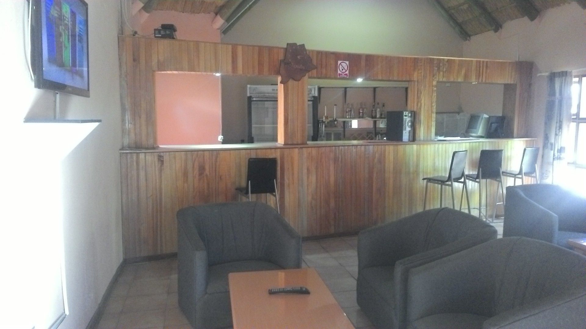 Un restaurante con paneles de madera, una zona de bar y asientos para los clientes.