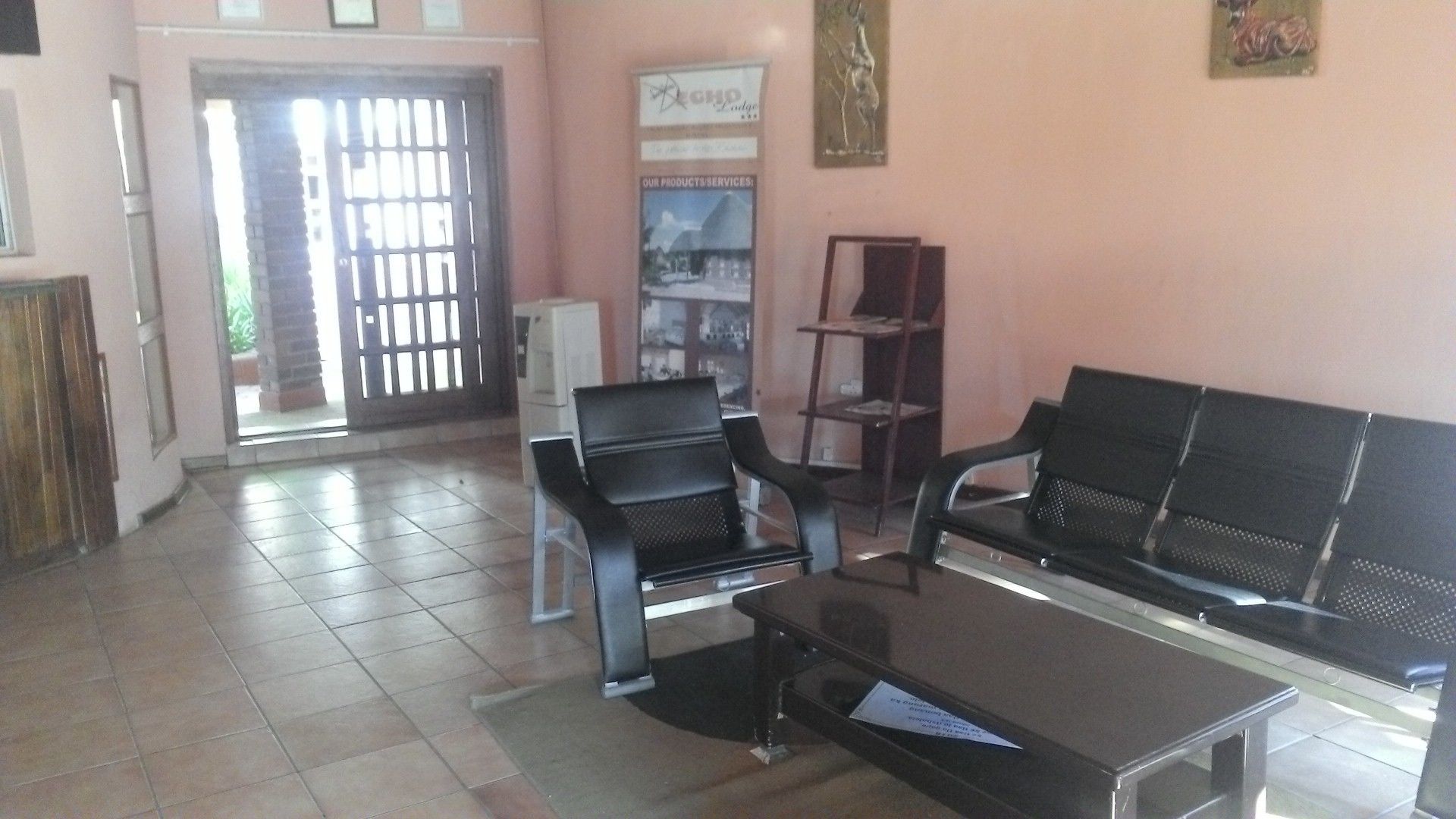A waiting area with a reception desk, two black chairs, a small table, and a tiled floor.