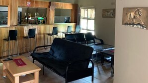 A spacious room with a high ceiling, a thatched roof, a bar area, and a seating area with a sofa and chairs. - Echo Lodge (Kang)