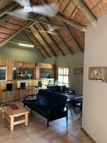 Una habitación amplia con techo alto, techo de paja, una zona de bar y una zona de estar con sofá y sillones.