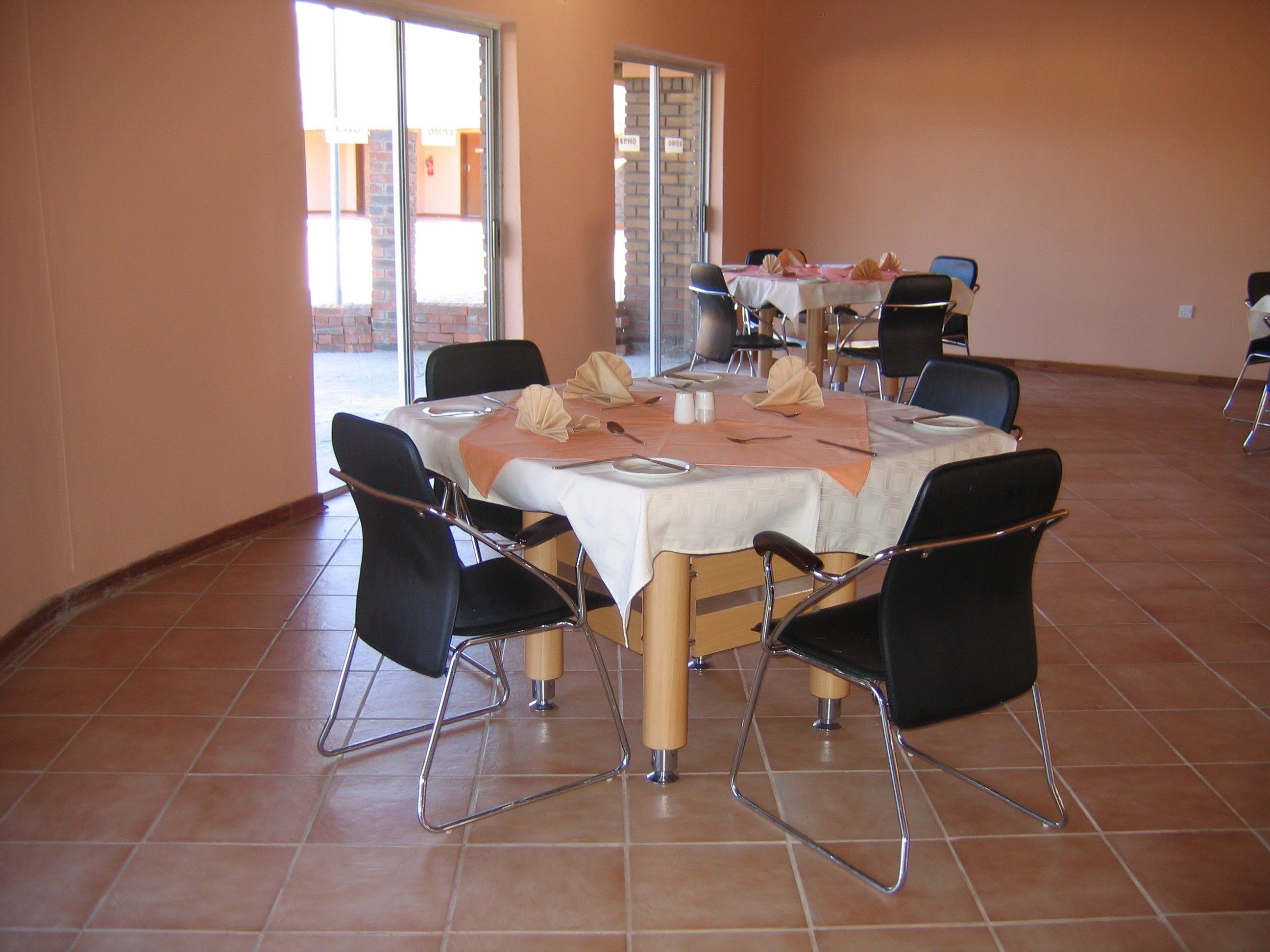 Comedor con una mesa redonda preparada para seis personas, rodeada de sillas negras con patas cromadas.