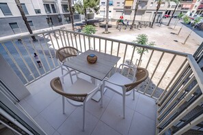 A balcony with a table and two wicker chairs, overlooking a playground and buildings. - Hotel Boutique La Brisa (Vilanova I la Geltru)