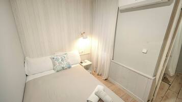 A hotel room with a bed, a nightstand, a lamp, a shower area, and a towel on the floor.