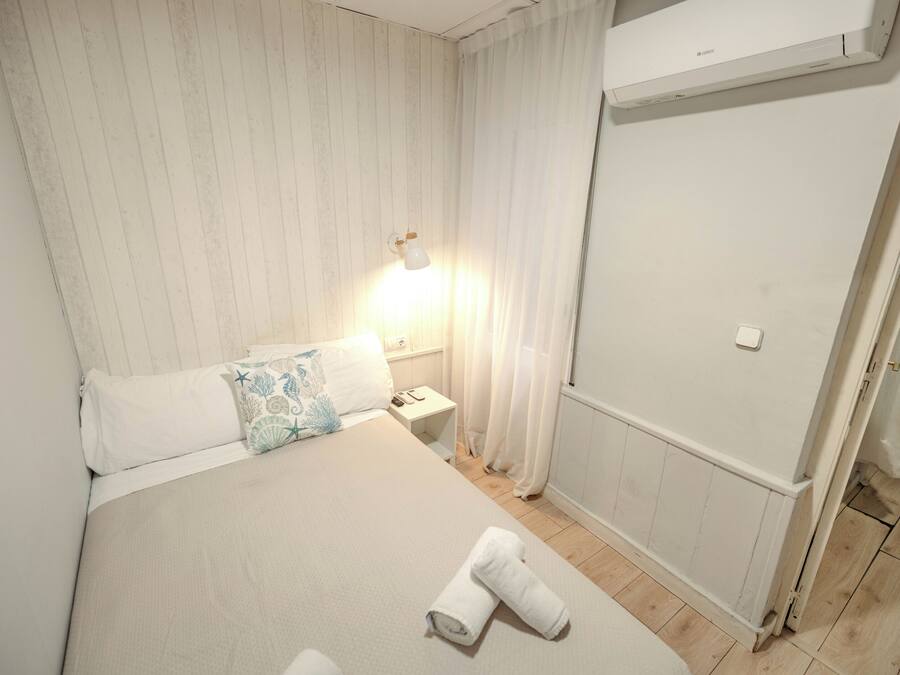 A hotel room with a bed, a nightstand, a lamp, a shower area, and a towel on the floor.