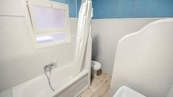 Un baño con bañera, inodoro y cortina de ducha.