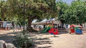Un parque infantil con tobogán, columpios y una estructura para escalar.
