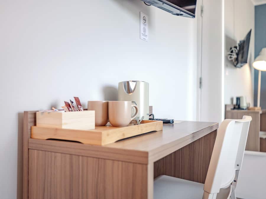 A wooden desk with a tray holding two cups, a coffee maker, and some books.