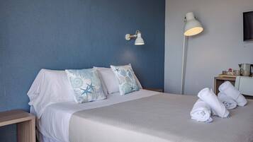 A hotel room with a bed, pillows, a bedside table, a lamp, and towels.