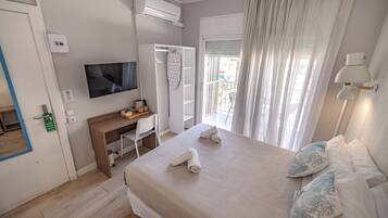 Ett hotellrum med en säng, ett skrivbord, en tv, en luftkonditioneringsanläggning och utsikt över omgivningarna.