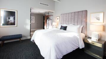A hotel room with a large bed, bedside tables, a bench, and artwork on the walls.