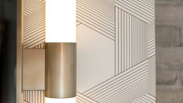 A modern interior with geometric patterned walls and a metallic cylindrical object, likely a light fixture.