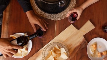 A wooden table with a bottle of wine, glasses, tortilla chips, and salsa.
