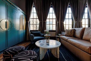 Un soggiorno moderno con un mobiletto blu, un divano blu, un tavolino rotondo e pouf decorati.