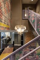 Una hall d'albergo con un lampadario moderno, una reception e una scalinata con ringhiere decorate.