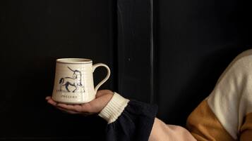 A hand holding a mug with a unicorn design against a dark background.