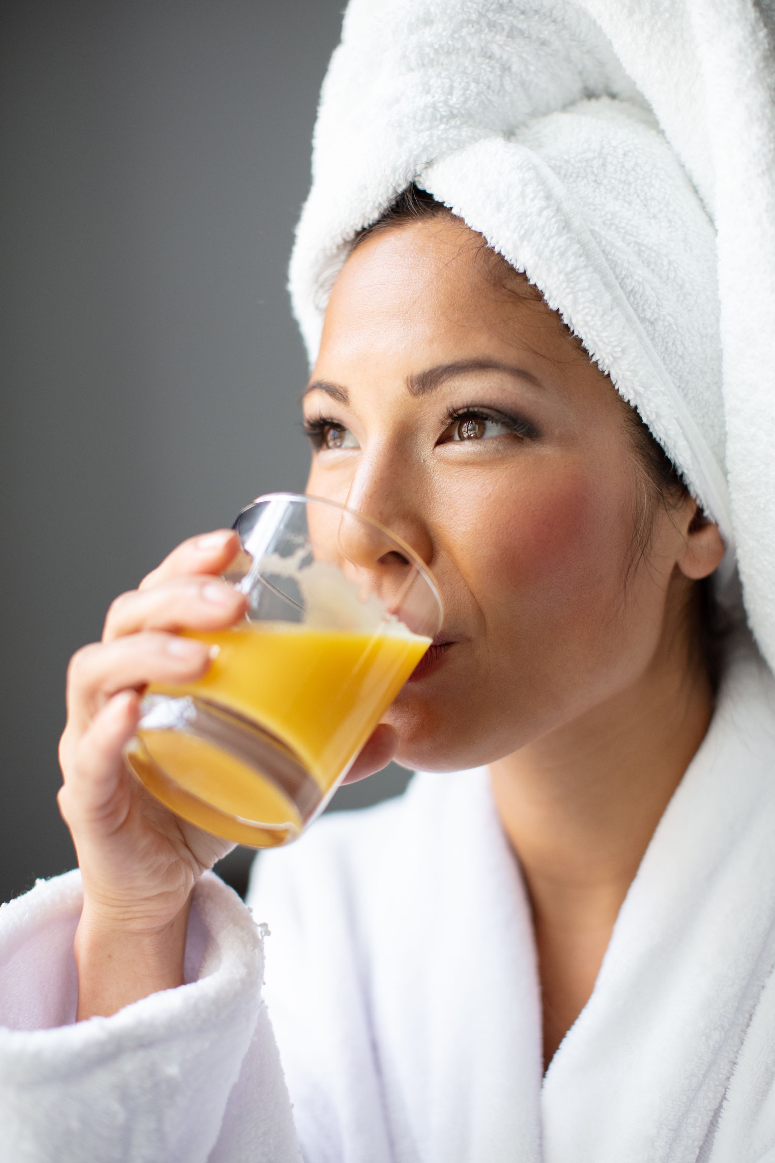Una persona con bata blanca sosteniendo un vaso de jugo de naranja.