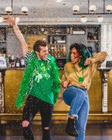 Due persone festeggiano tra coriandoli in un bar.
