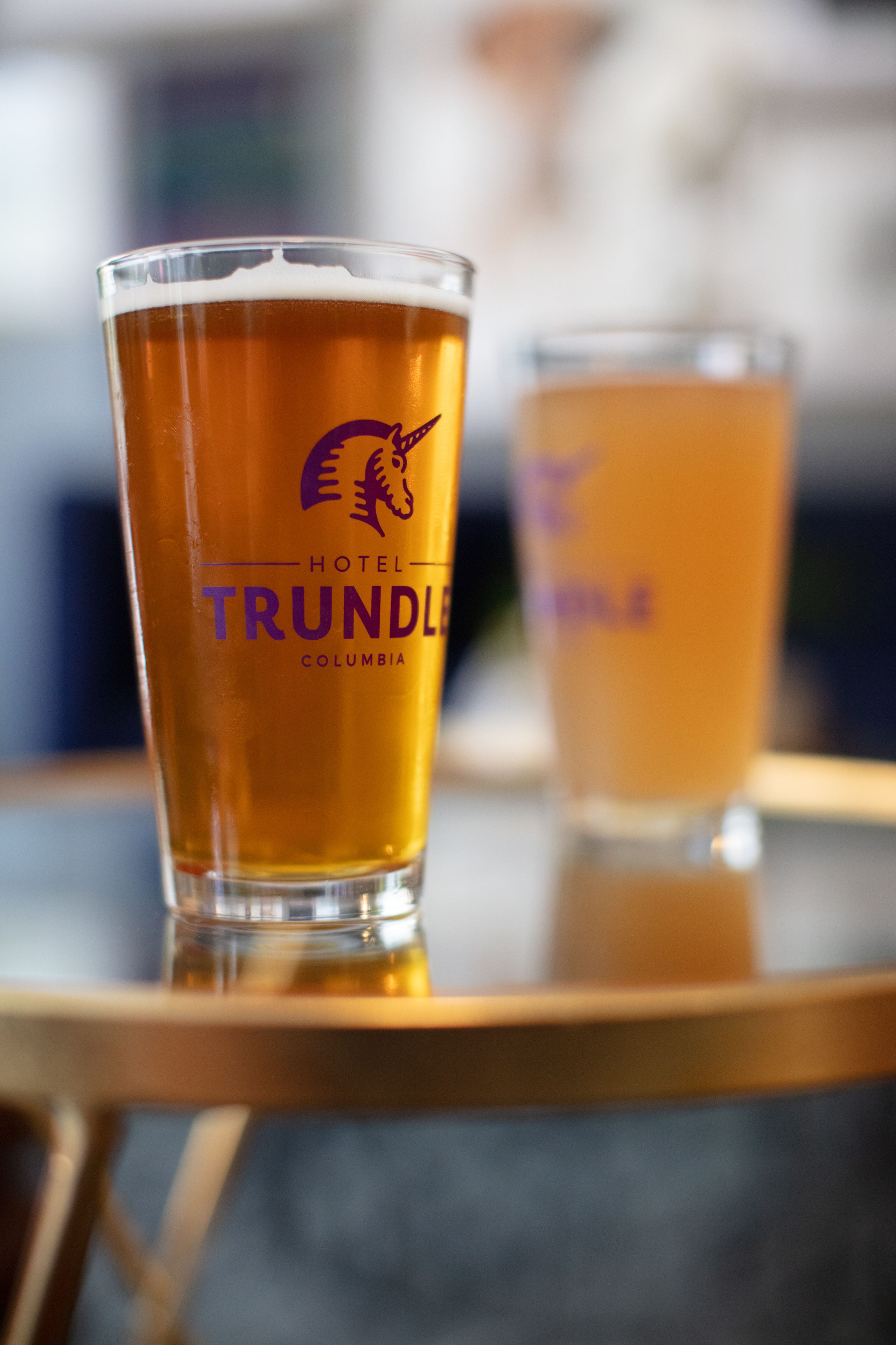 Two glasses of beer on a table with a blurred background.