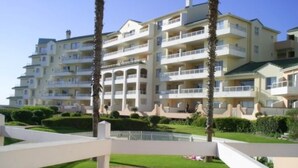 Ein mehrstöckiges Hotel mit Balkonen, einem Schwimmbad und gepflegten Gärten.