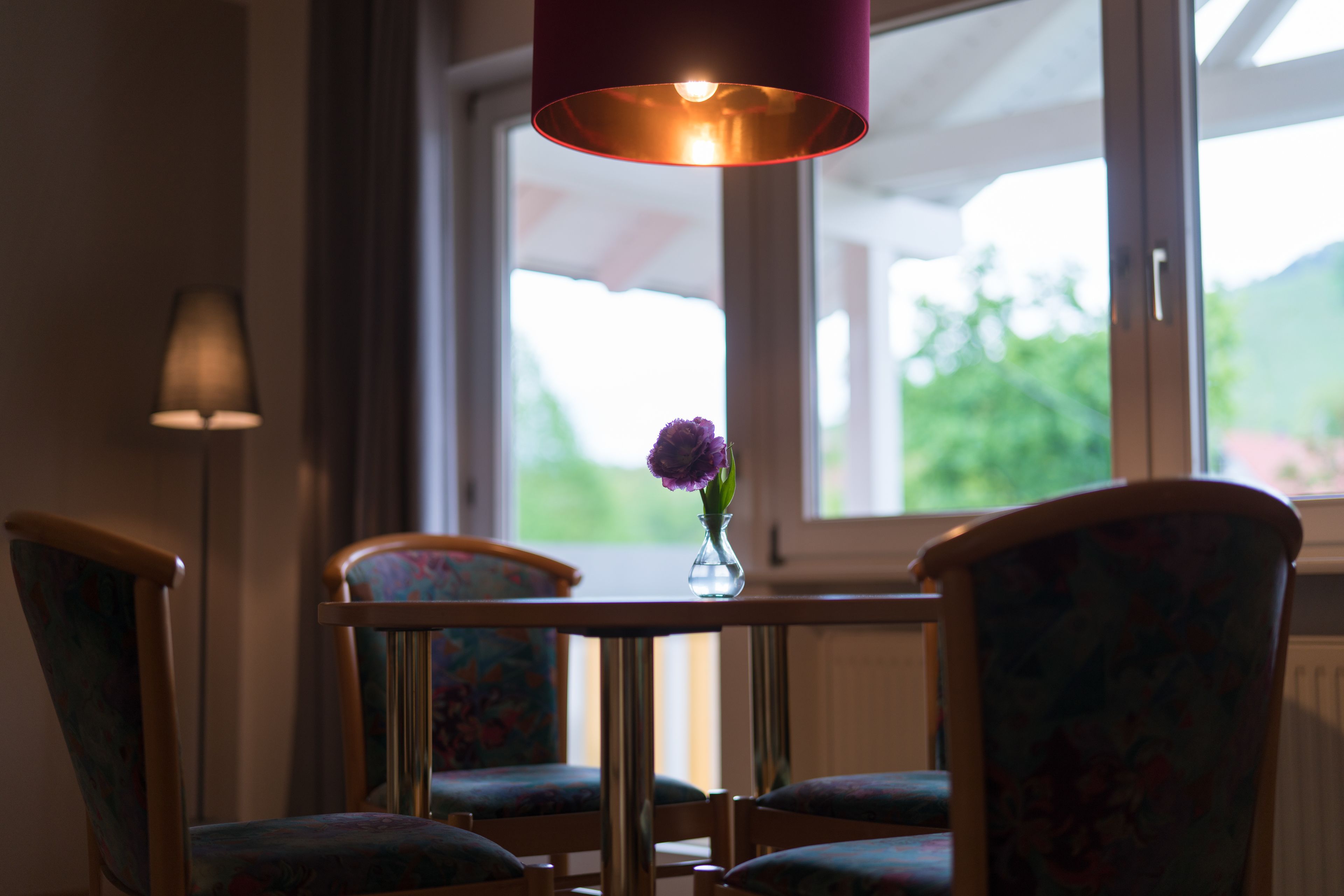 A dining area with a table, chairs, and a vase with flowers.