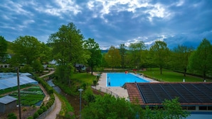 A large swimming pool surrounded by lush greenery and a clear blue sky. - Hotel Linde Durbach (Durbach)