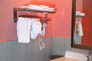 A bathroom with a sink, a towel rack with folded towels, and a hairdryer plugged in. - 4 Star Motel (Los Angeles)