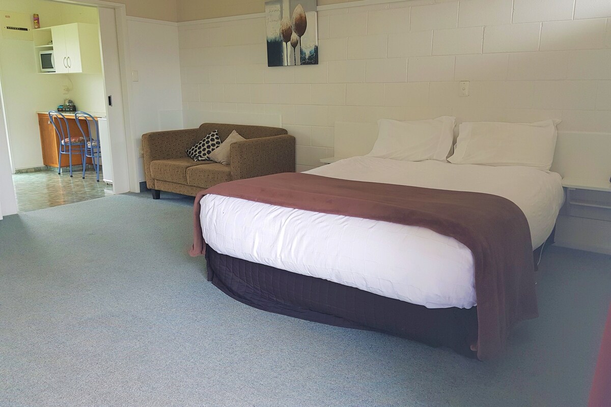 A bedroom with a bed, a sofa, and a small table with a chair.