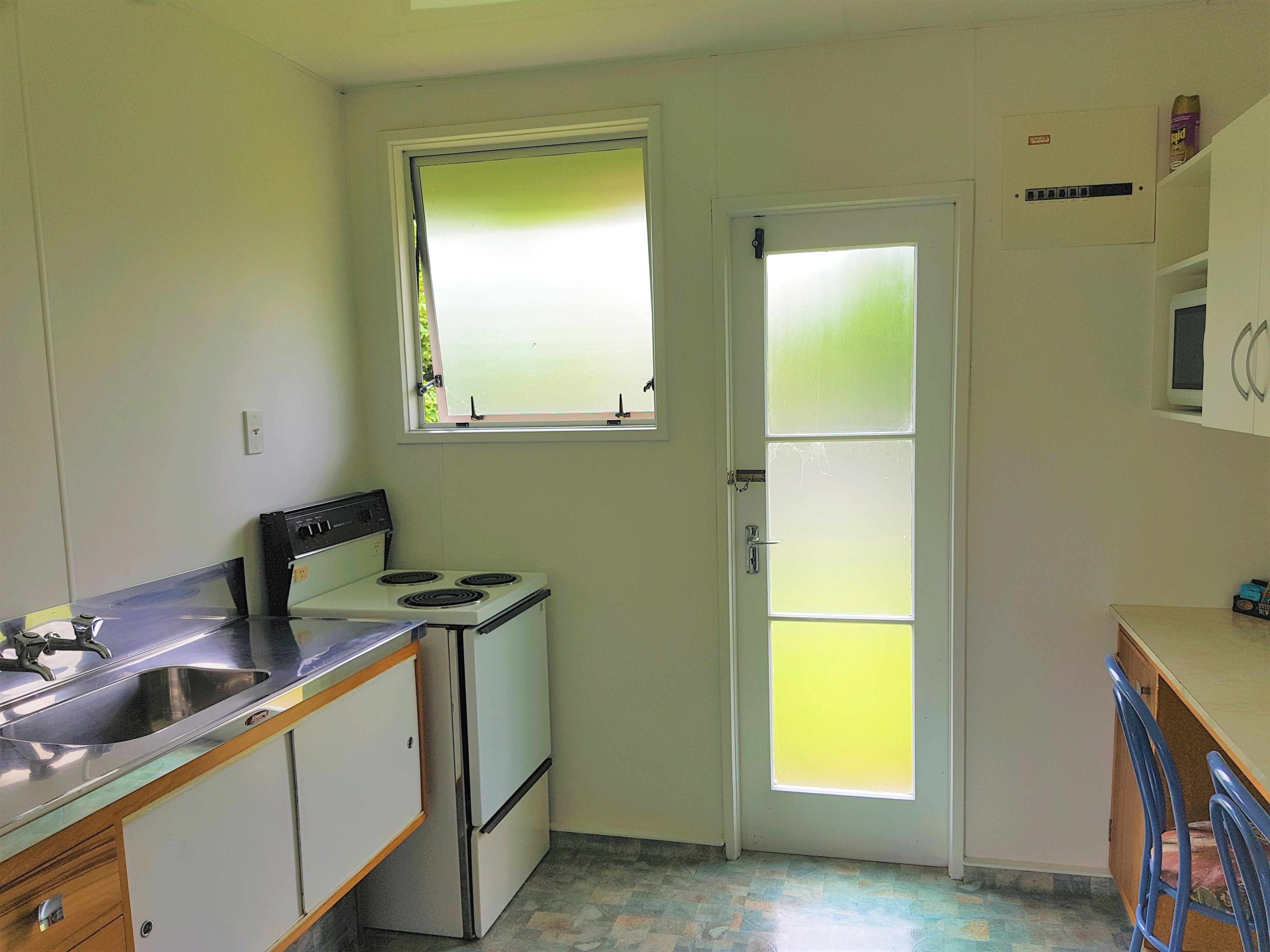 Una cocina compacta con estufa, lavamanos y ventana.