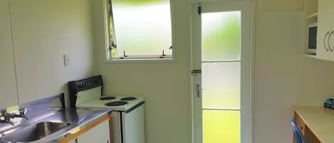 A compact kitchen with a stove, sink, and window.