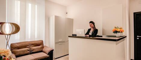 A modern reception area with a sofa, a desk, and a refrigerator.